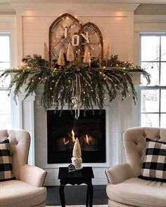 a living room with two chairs and a fire place in front of a christmas tree