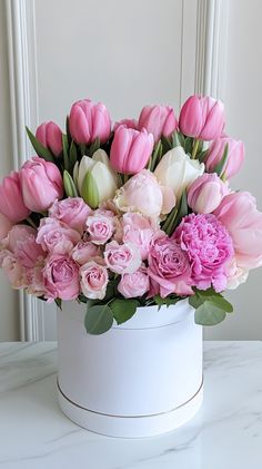 pink and white tulips in a white container on a table