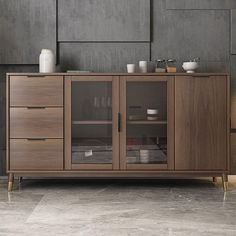 a large wooden cabinet with glass doors and drawers in a room that has grey walls