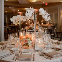 the centerpieces on this table are filled with flowers, candles and napkins