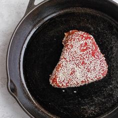 a piece of meat in a frying pan with powdered sugar on the top