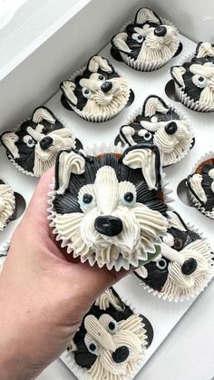 a hand is holding up some cupcakes that look like dogs