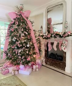 a decorated christmas tree in a living room with pink bows and stockings on the mantle