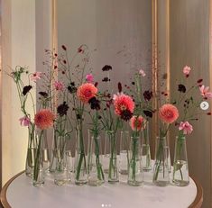 there are many vases with flowers in them on the table next to each other