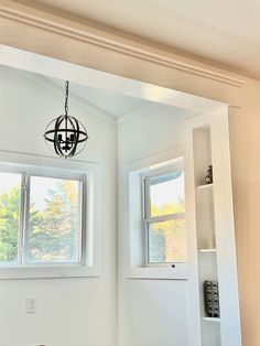 an empty room with two windows and a light fixture hanging from the ceiling above it