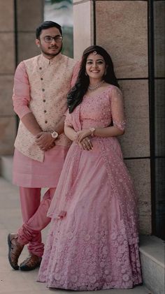 two people standing next to each other wearing pink outfits and posing for the camera with their arms around each other