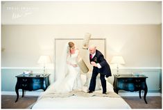 a bride and groom posing for a photo on the bed in their hotel room with two nightstands