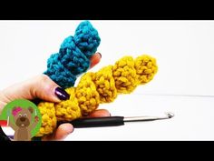 two crocheted objects are being held by someone's hand with a pair of scissors