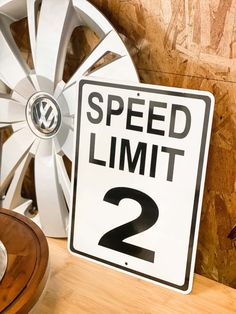 a speed limit sign sitting on top of a wooden table next to a white wheel