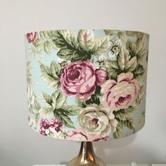 a lamp that has flowers on it sitting on a table next to a bookcase