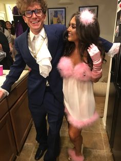 a man in a suit and tie standing next to a woman wearing a pink feather boa