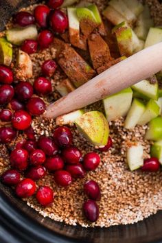 apples, cranberries and cinnamon sticks are mixed together in a slow cooker