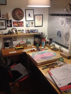 a desk with art supplies and pictures on the wall