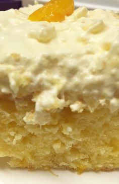 a piece of cake with white frosting and an orange slice on the top is sitting on a plate