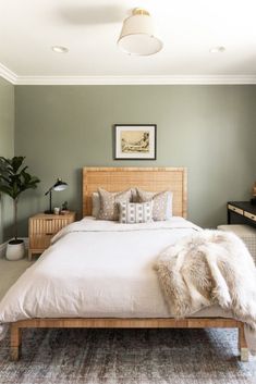 a bedroom with a bed, nightstands and plants on the wall behind it in shades of green