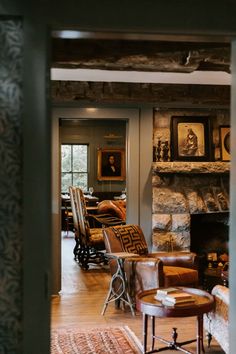 a living room filled with furniture and a fire place next to a stone fireplace covered in framed pictures