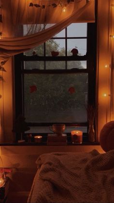 candles are lit in front of a window that is decorated with white curtains and lights