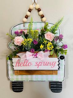 a wooden sign with flowers hanging from it's side and the words hello spring on it