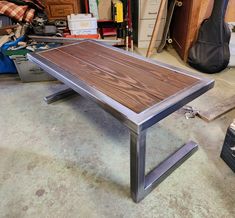 a wooden table sitting on top of a metal frame in a room filled with tools