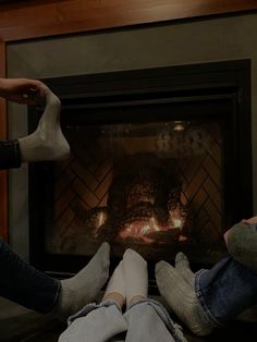 two people sitting in front of a fireplace with their feet up on the fire place