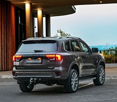 the rear end of a silver ford suv parked in front of a building with an ocean view