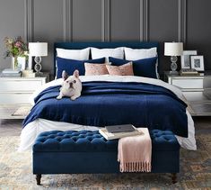 a dog laying on top of a blue bed in a room with gray walls and furniture