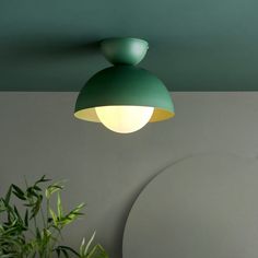 a green ceiling light hanging from the ceiling in a room with a potted plant