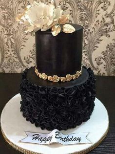 a black and gold birthday cake with flowers on top