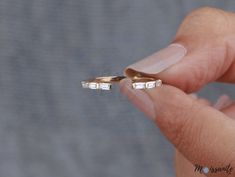 a person is holding two gold rings with white diamonds on each one and the other side