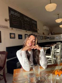 a woman sitting at a table in a restaurant with her eyes closed and hands on her face