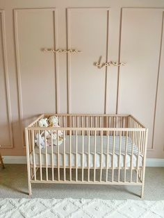 a baby crib in a pink room with white carpet and wall paneling on the walls