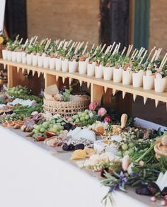 an assortment of food is displayed on a long table with cups and sticks sticking out of them