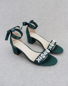 a pair of green high heeled shoes with bows on the side and jewel embellishments