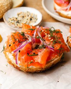 an open face bagel with smoked salmon and onions on it, topped with dill