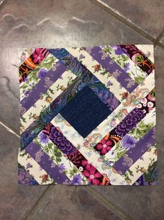 a purple and white patchwork quilt on a tile floor with blue center piece in the middle