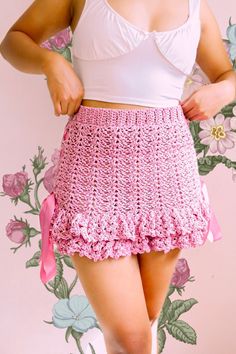 a woman wearing a pink crochet skirt and white tank top with her hands on her hips