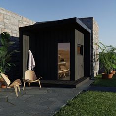 a small black shed sitting on top of a lush green field next to a stone wall