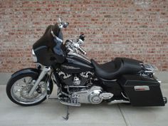 a black motorcycle parked in front of a brick wall