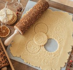 a rolling dough on top of a wooden table next to oranges and other decorations