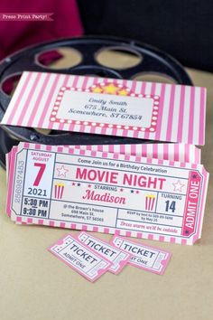 two pink and white movie tickets sitting on top of a table