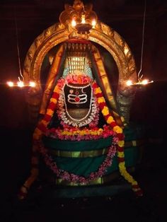 the statue is decorated with candles and garlands for diwaling it's eyes