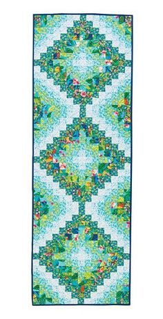 a blue and green quilt with an intricate design on the front, along with a white background