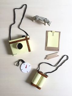 an assortment of items are displayed on a white surface, including a camera and pencils