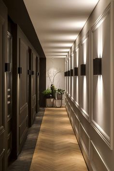 a long hallway with lights on the wall and plants in potted planters next to it