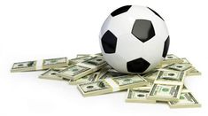 a soccer ball sitting on top of a pile of hundred dollar bills in front of it