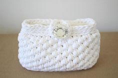 a white crocheted basket with a button on it