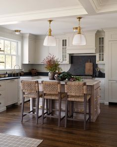 a kitchen with white cabinets and an island in front of the countertop, surrounded by wicker bar stools