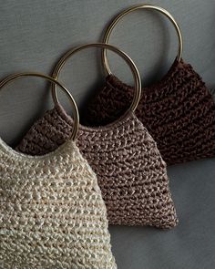 three crocheted purses with gold rings hanging from them