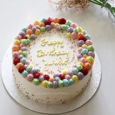 a birthday cake with the words happy birthday written in frosting surrounded by multicolored decorations