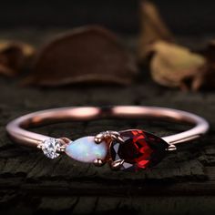 a red and white ring sitting on top of a piece of wood with leaves in the background